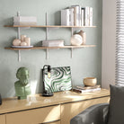 Modern interior with living room storage shelves, books, and decorative items against a light green wall.