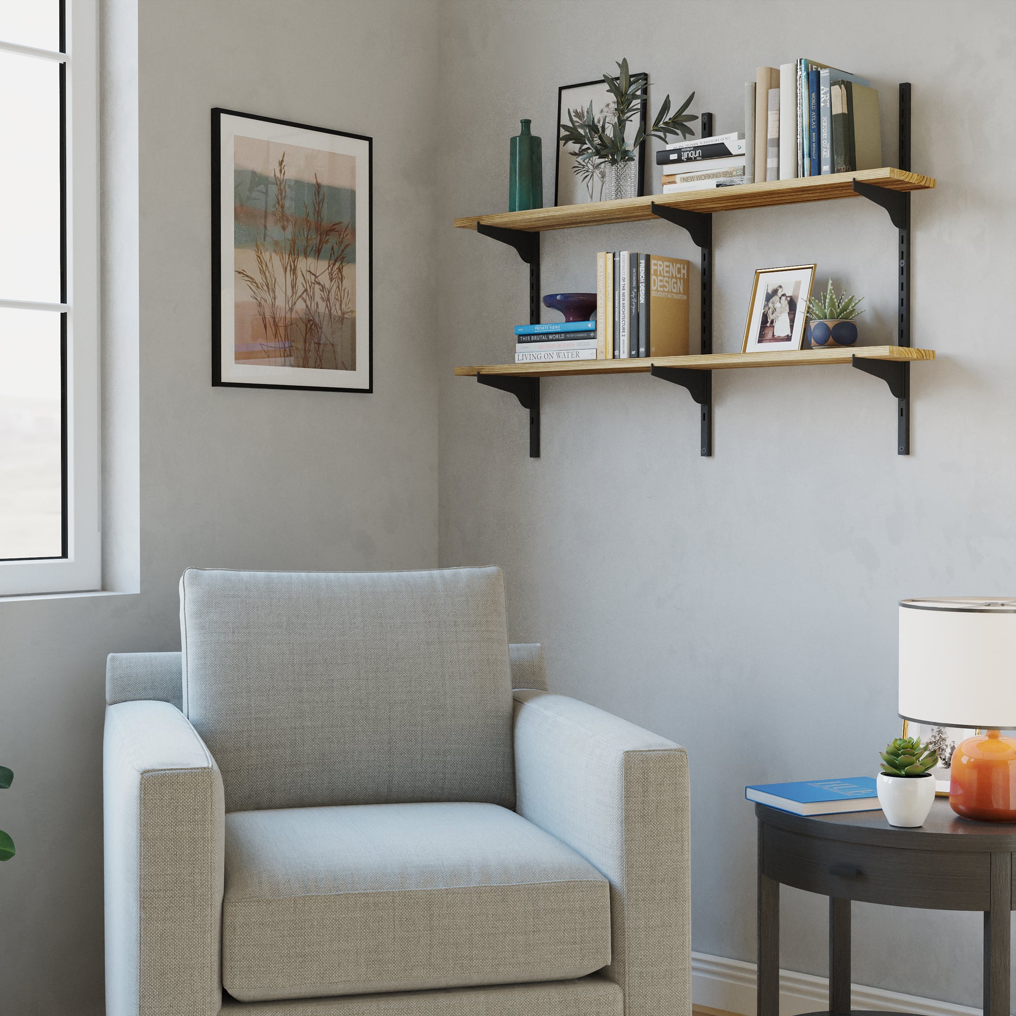 Reading nook with a gray armchair under a two-tier floating book shelf with adjustable black brackets featuring books, plants, and decor accents on light wood boards and black brackets.