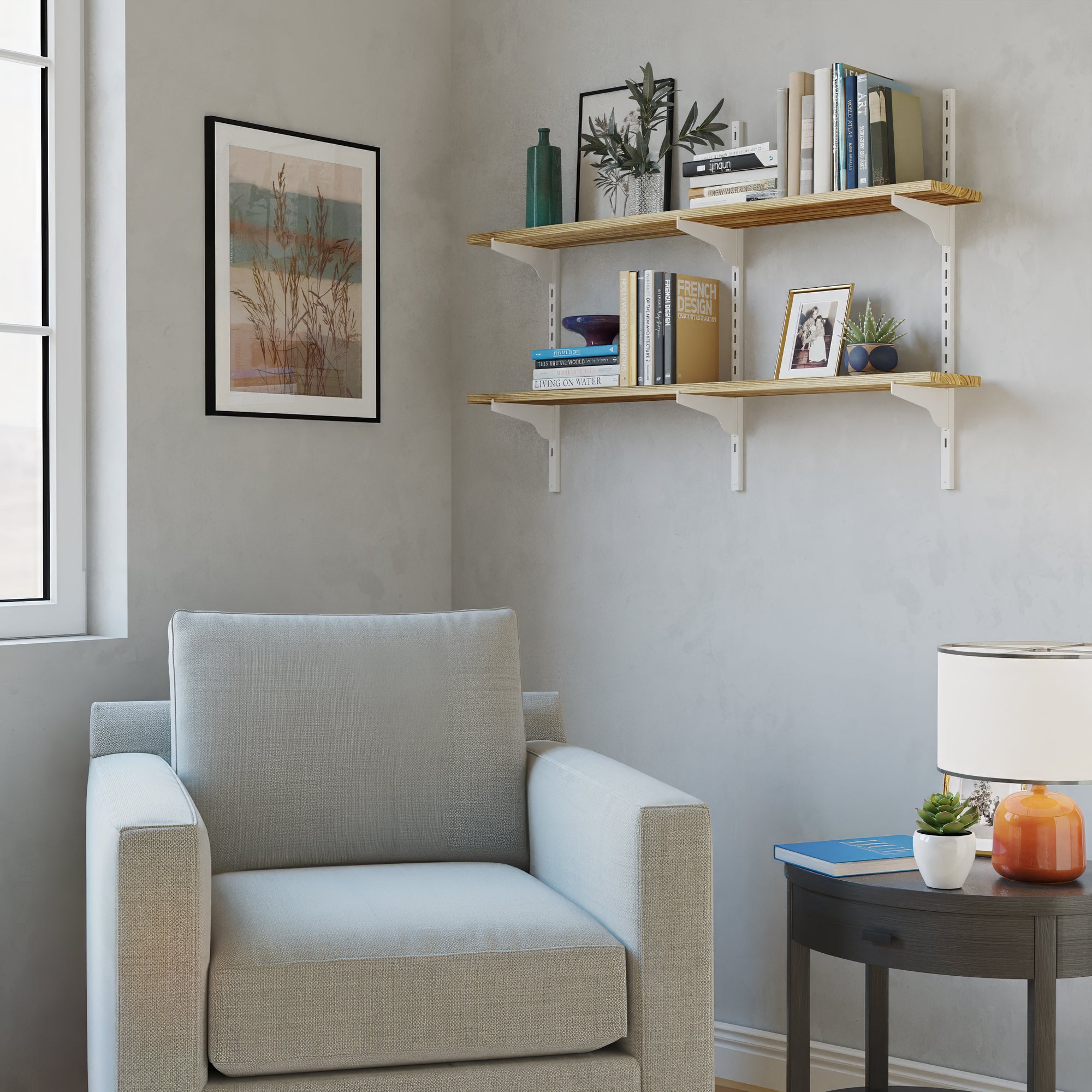 Beige armchair in a living room setup with 2 tier wall mounted shelf, books, and decor items.