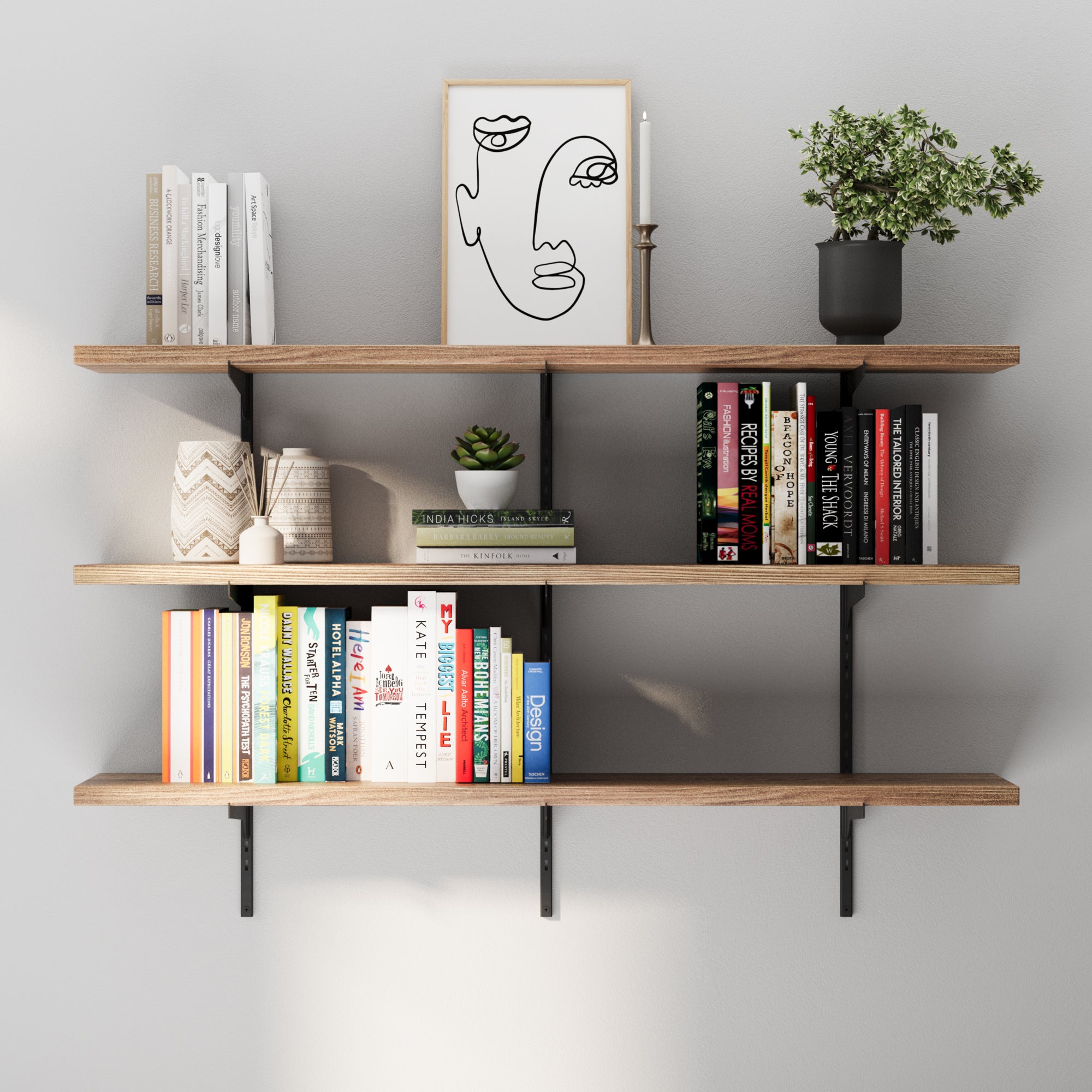 Modern wall display with three floating shelves in black metal and wood finish, styled with books, decor pieces, framed artwork, and greenery for a clean interior look.