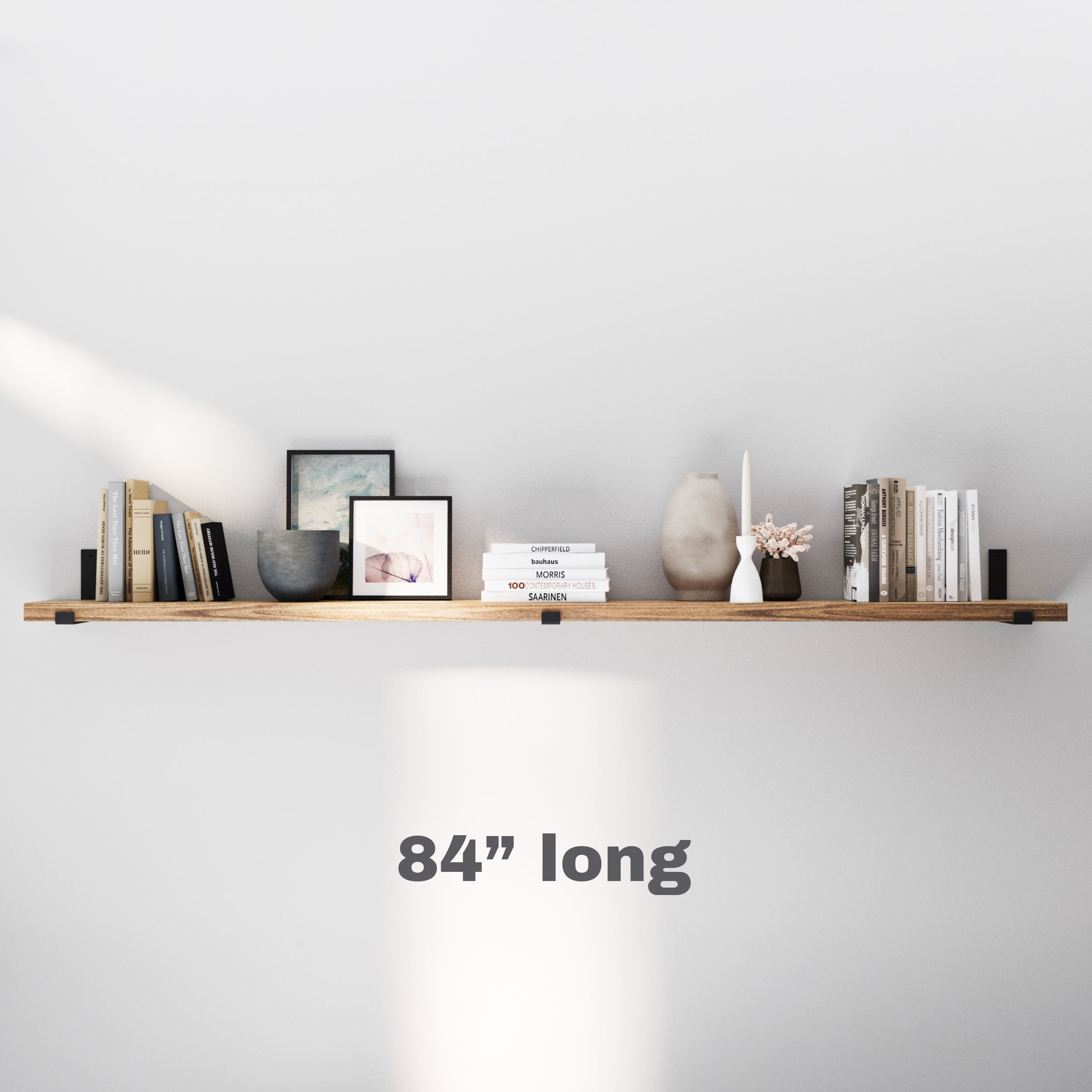 A 84 inch long shelf stylishly organizes books, vases, and photo frames, making it ideal for minimalist spaces with functional elegance.