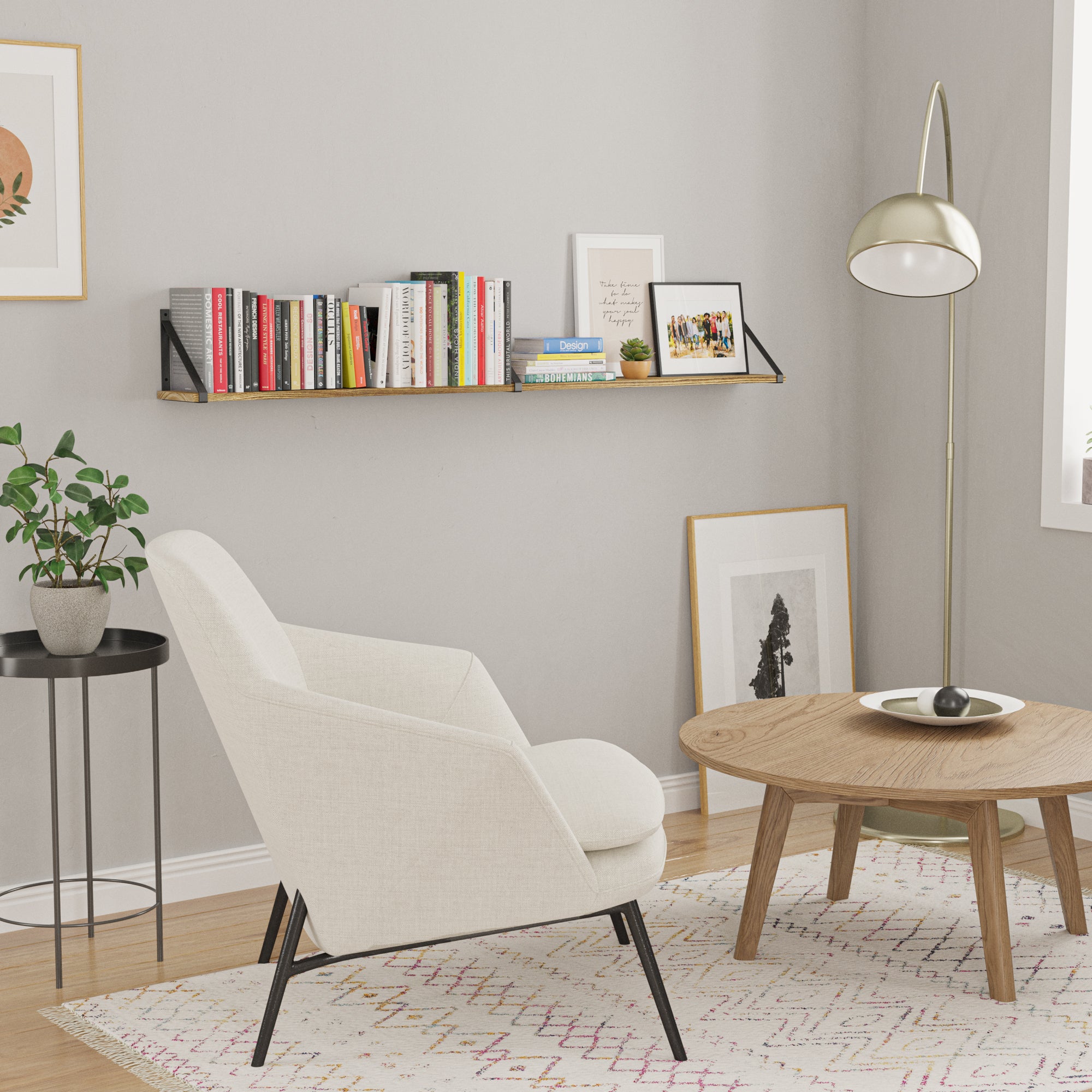 A cozy, modern living room corner with a gray wall. On the wall, there's a floating wall shelf packed with colorful books, and some framed photos leaning against the wall.