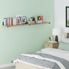 A wall shelf burnt above a bed, filled with books and decor items against a green wall.