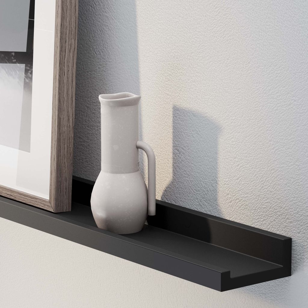 A close-up of a picture frame and ceramic jug on a 60'' black LAGOS floating ledge against a white textured wall