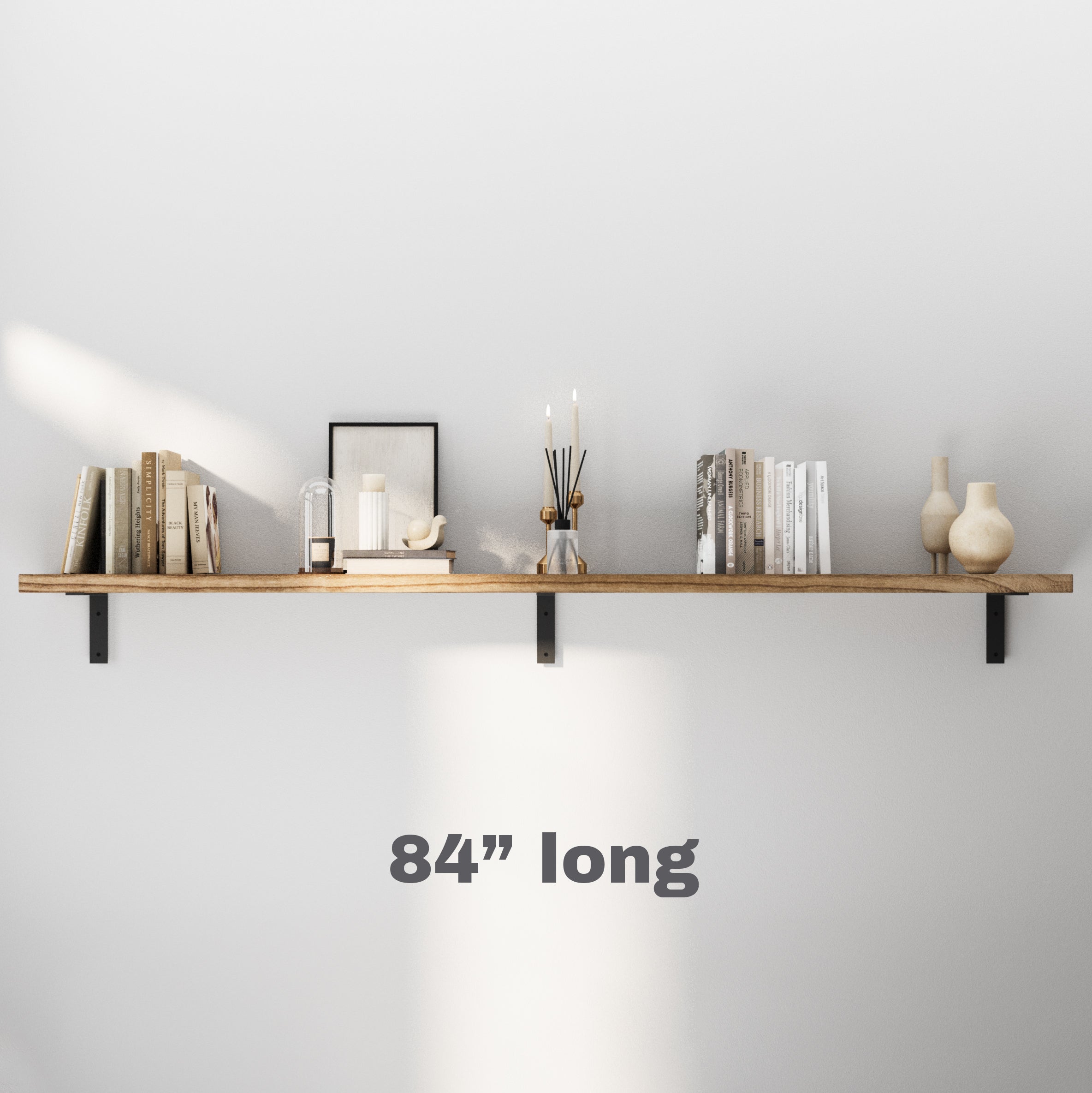 A long three-bracket floating long shelf adorned with books, candles, and artistic elements, perfect for maximizing space.