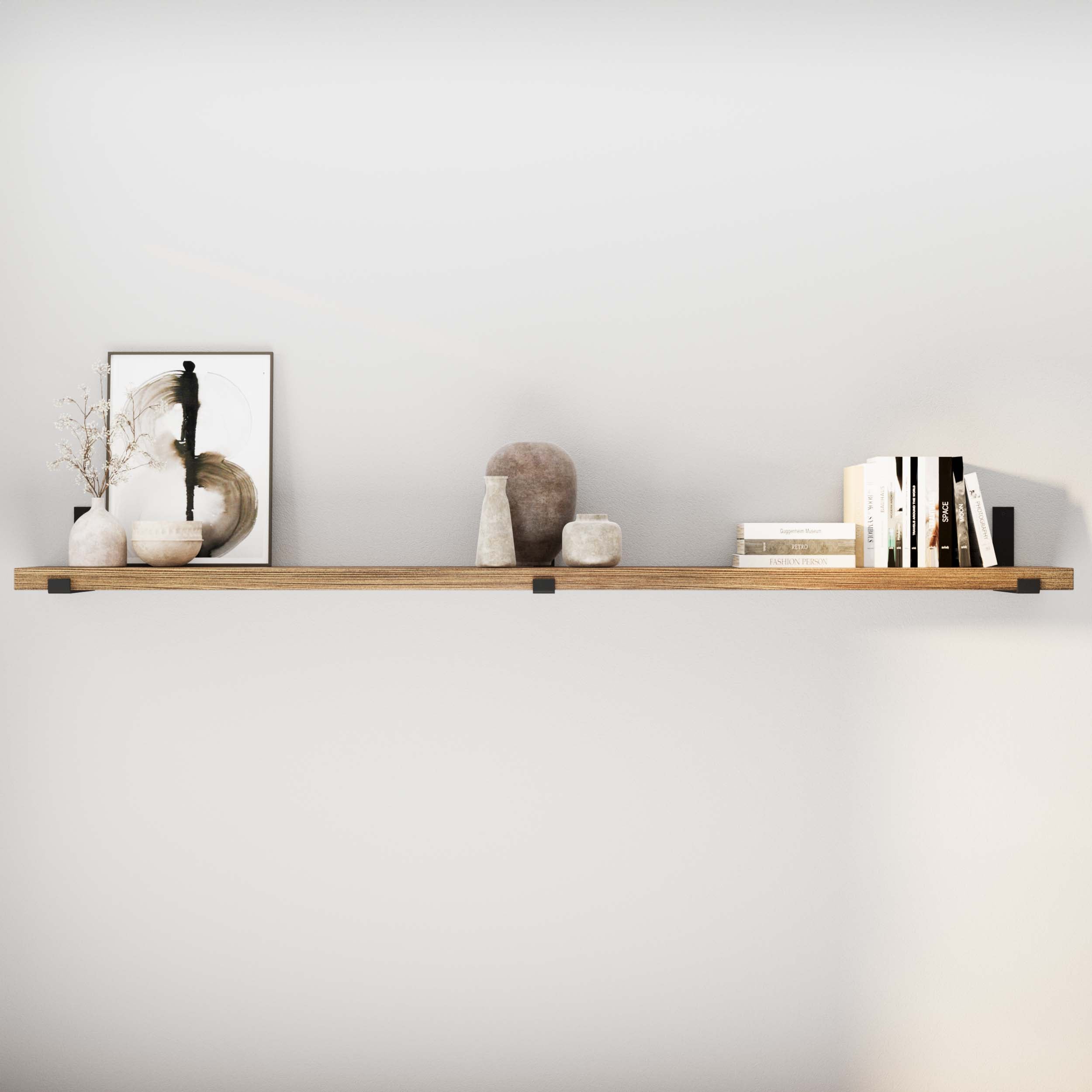 Decorative objects and books on a 72 inch floating shelf against a plain wall.