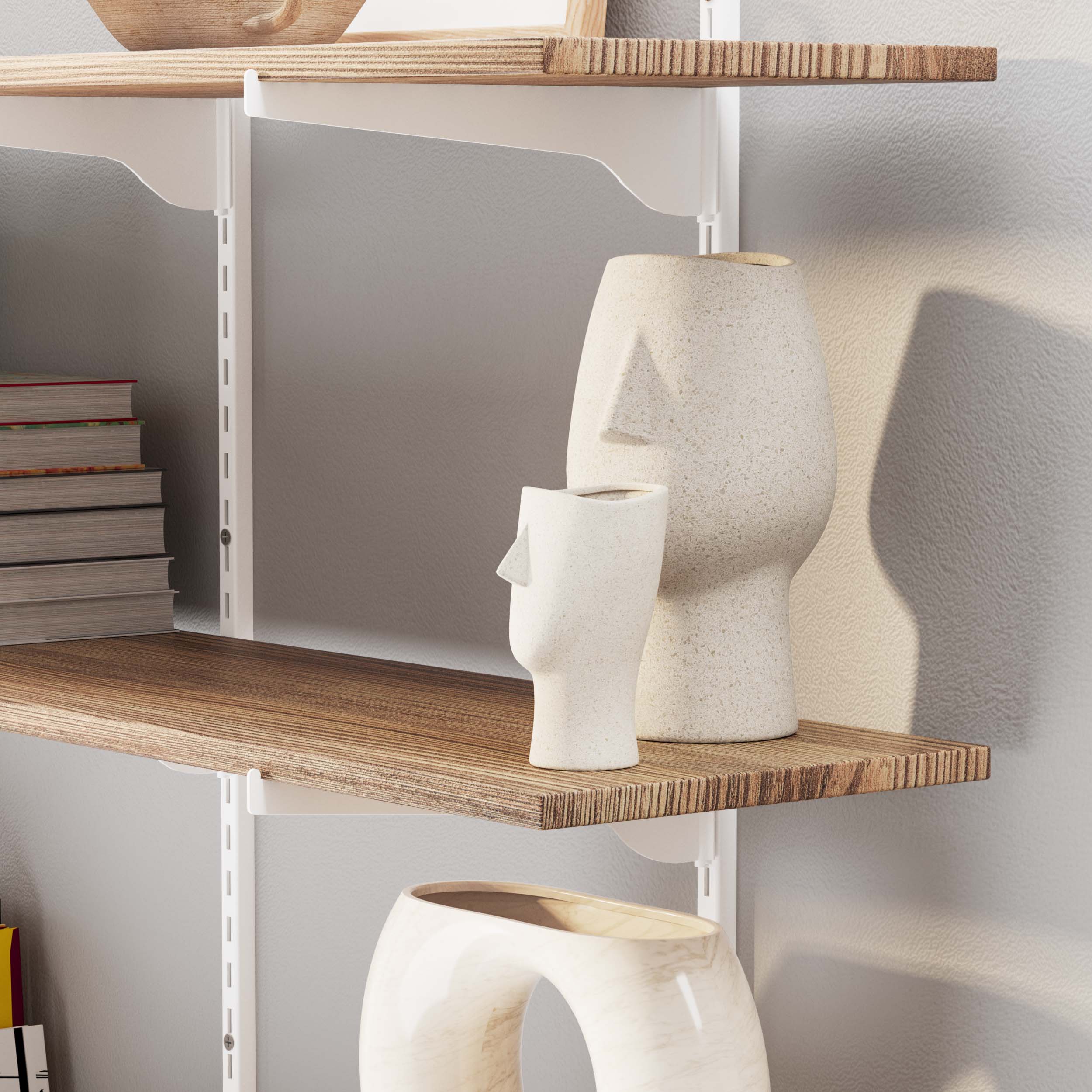 A display shelf with abstract face vases casts soft shadows on a textured wall, warm and artistic.