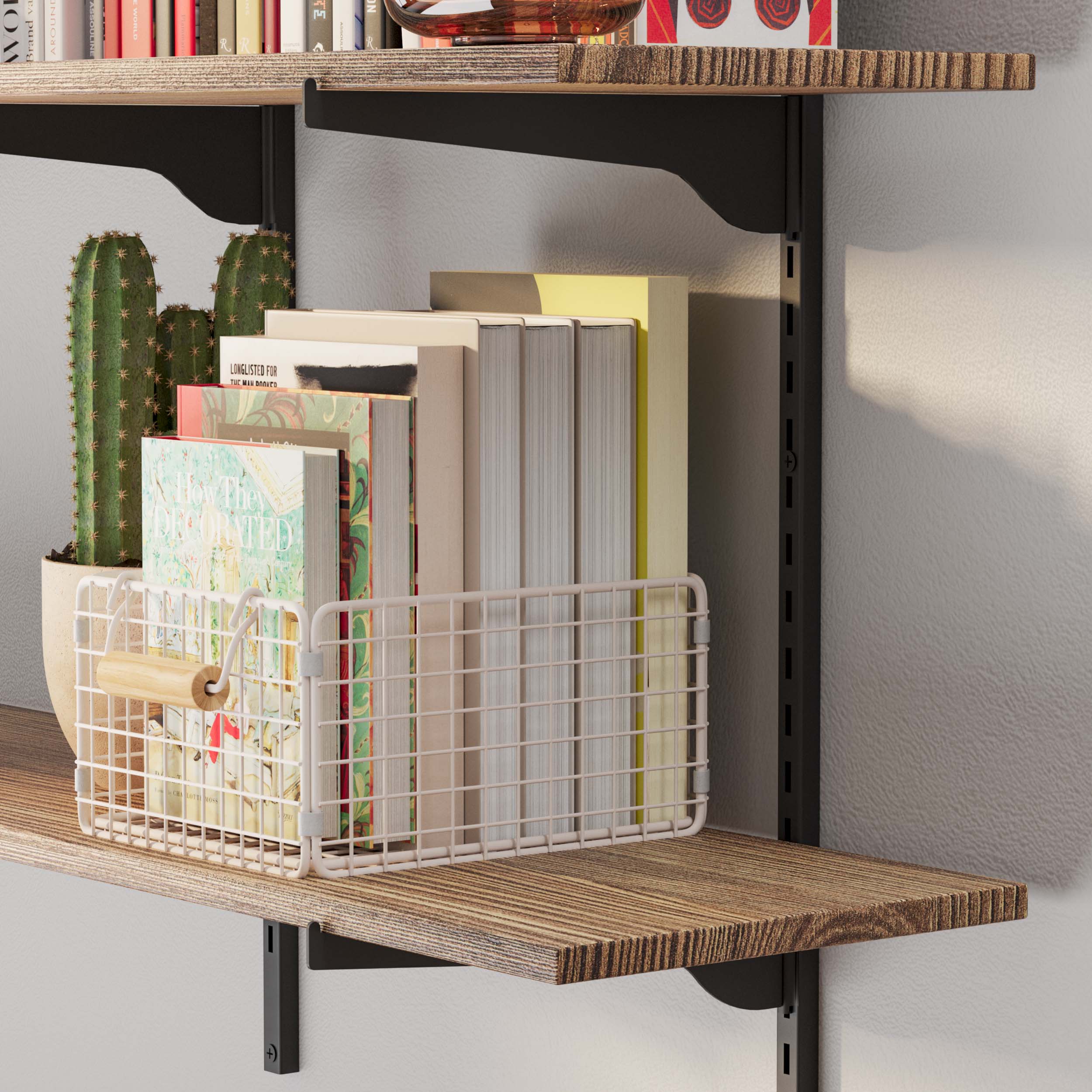 Close-up of a burnt wall mounted shelf with a cactus and a wire basket holding books, showcasing the textured wood surface and black brackets.