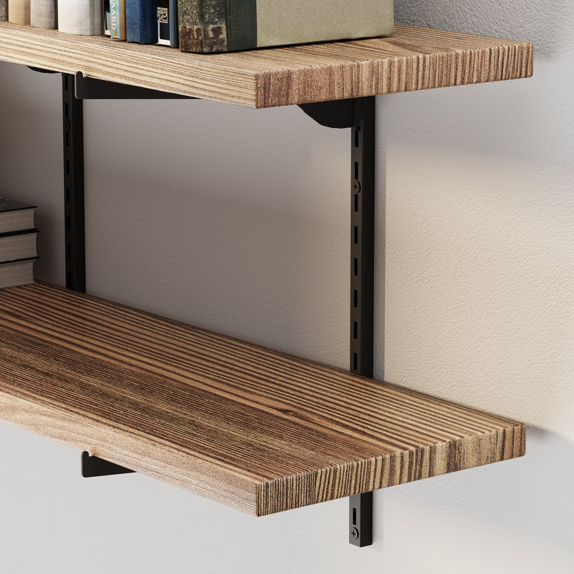 Close-up of a 2 tier shelf with black metal brackets, holding a few books and placed above another empty wall shelf.