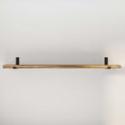 Empty 60'' wooden floating shelf with black brackets on a white wall.