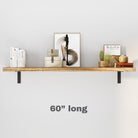 A 60 inch wooden floating shelf with black metal brackets mounted on a wall. It holds books, a framed artwork, and decorative items, showing its clean and minimal design for wall decor.