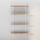 Empty wooden shelves with white brackets against a grey wall.