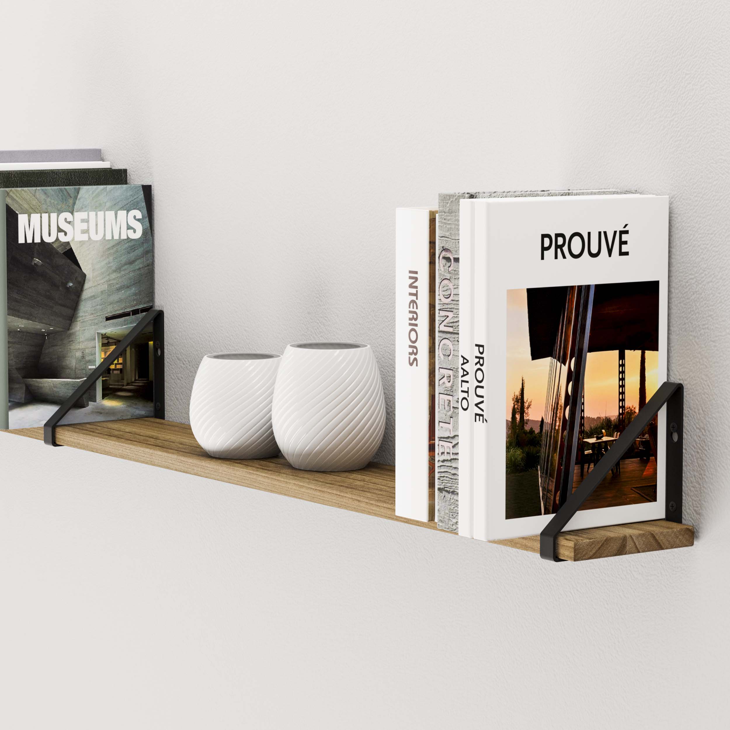 Close-up of a wooden shelf displaying art and design books alongside textured white vases, creating a minimalist aesthetic.