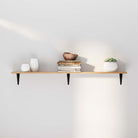 A simple floating shelf with black brackets, styled with books, vases, and a succulent. Clean lines and soft lighting enhance its minimalist charm.