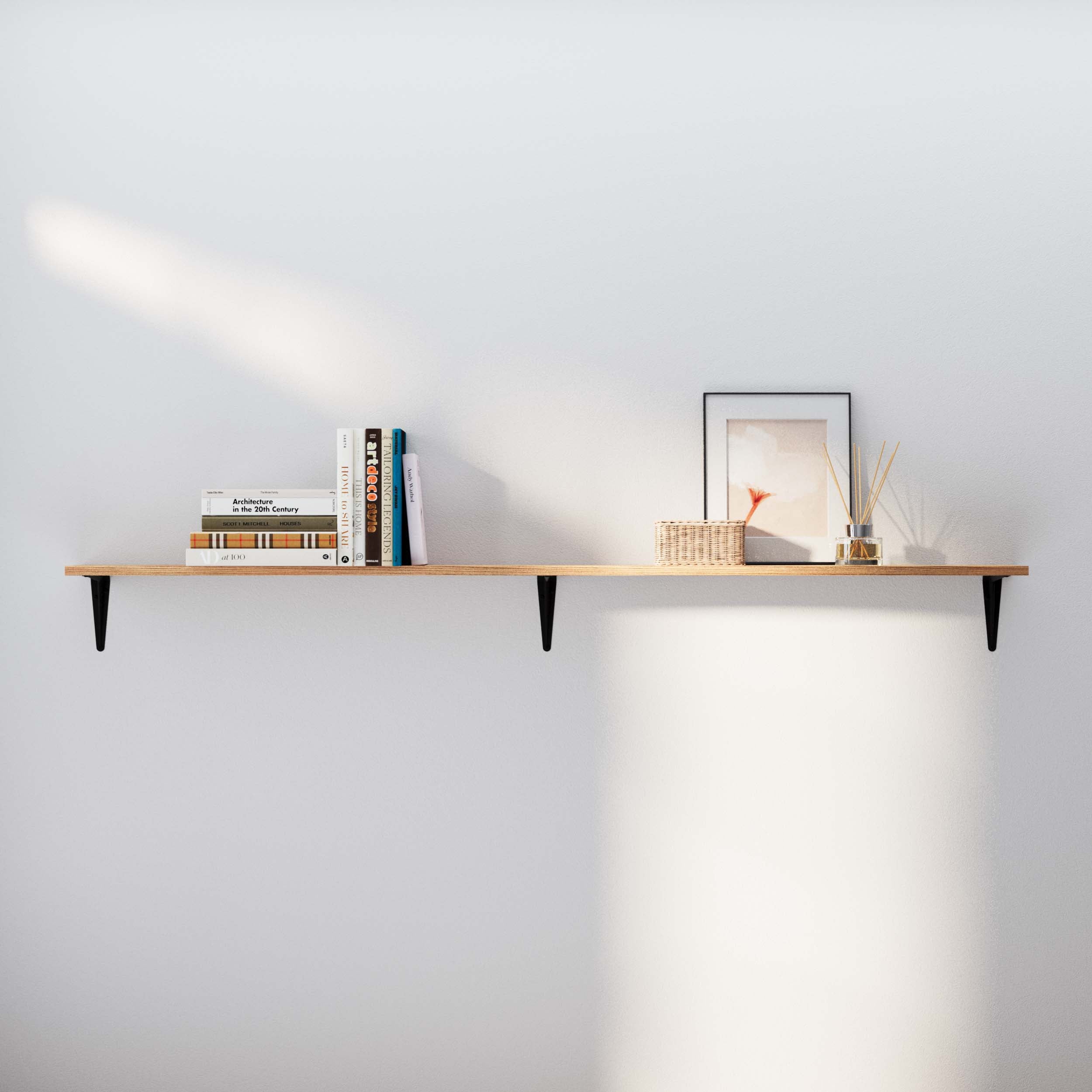 Elegant floating shelf displaying books, a framed abstract artwork, and a glass diffuser, enhancing a simple wall.