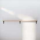 Empty organizer shelf burnt on a plain wall accentuated by soft lighting, demonstrating the shelf's sleek design.