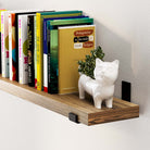 Close-up of a modern long shelf burnt holding books and a cute cat-shaped planter. Perfect for adding a touch of charm and functionality to your home and wall decor.