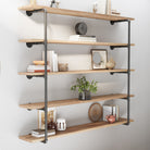 The PIPE 60'' Floating Pipe Shelves - 5 Tier - Burnt elegantly arranged with a mix of books, plants, and decorative items. The combination of iron pipe brackets and burnt wooden storage shelves creates a striking visual appeal.