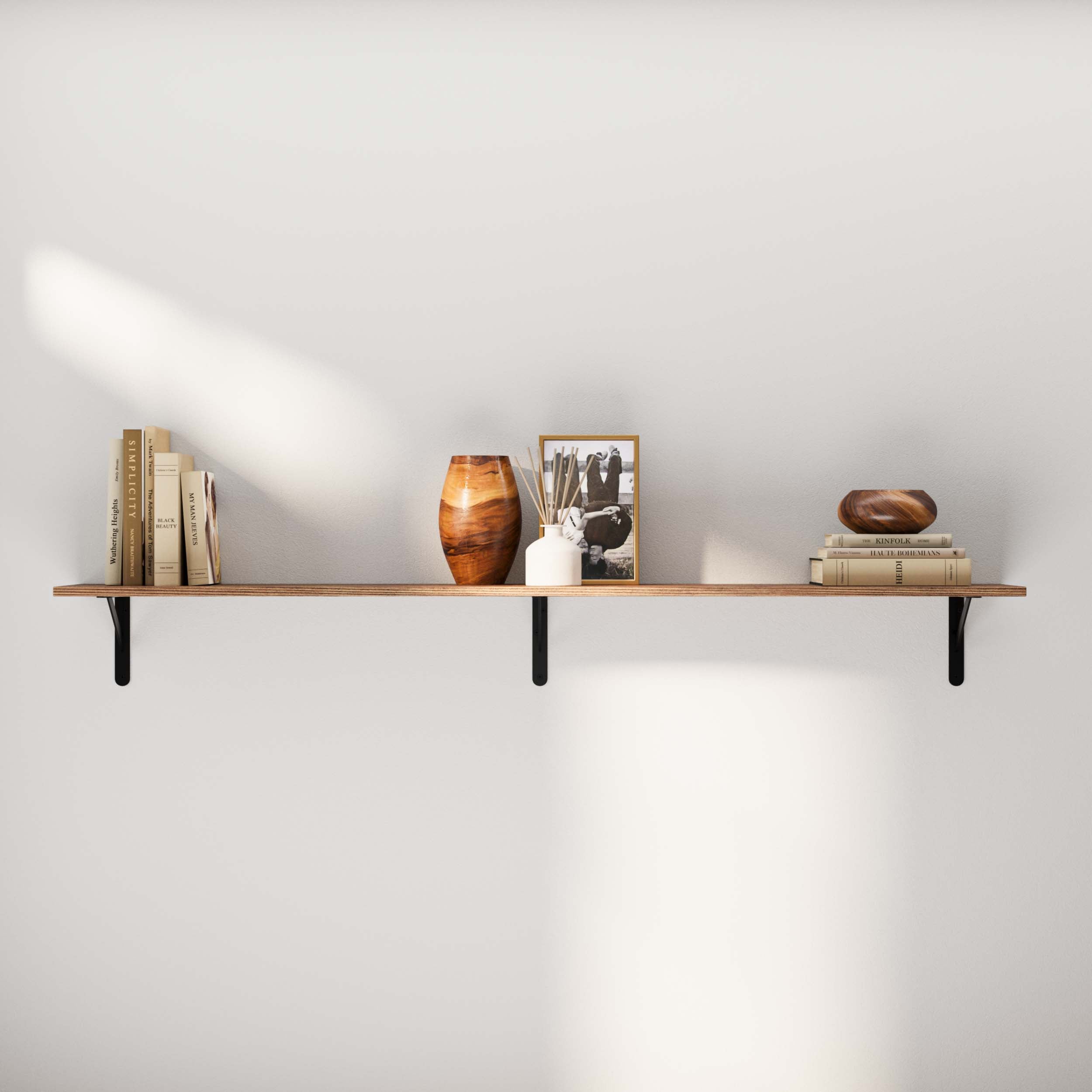 Simple, minimalistic living room wall shelf featuring a wood plank supported by black metal brackets. Decorated with books, a vase, and a picture frame for an elegant, uncluttered look.