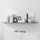 A 48 inch wooden wall shelf decorated with monochromatic books, candles, and minimalist ceramics, offering a modern and clean aesthetic.