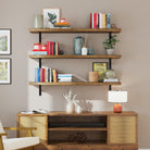 3 farmhouse shelves with rich burnt finish above a wooden console table, filled with books, vases, and decor pieces. The black brackets add contrast to the warm wood tones.