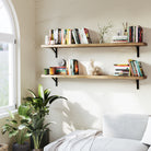 Bedroom corner with two bedroom shelves wall mounted, styled with books and decor items. Positioned above a cozy bed, it integrates nature-inspired accents and sunlight streaming through an arched window.