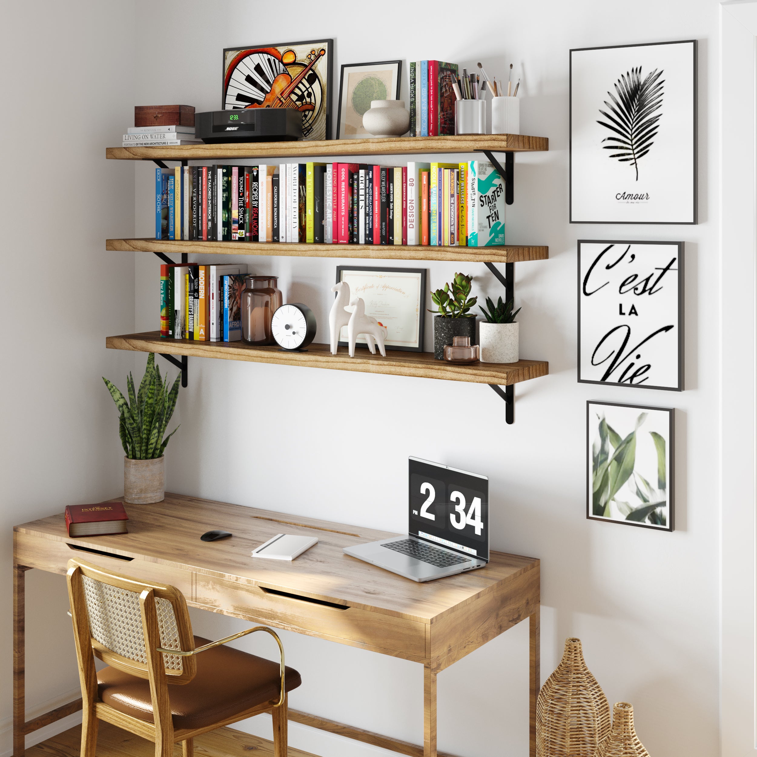 Home office featuring three wooden office shelves over a rustic desk, adorned with books, plants, and art prints for an inspiring workspace.