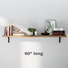 A 60 inch long wall bookshelf styled with books, a framed plant print, a candle, and a decorative bowl. The minimalist arrangement highlights functionality and elegance.