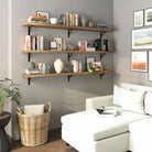 A cozy living room featuring three wall-mounted long wooden shelves, styled with books, vases, and plants, creating a modern, organized, and stylish decor accent.