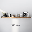 A 84 inch extra long wooden wall shelf with metal brackets, showcasing a modern aesthetic. Decorated with neutral books, black-and-white art, and ceramic pieces, it creates a sleek and balanced display.