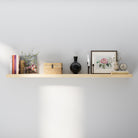 A 60" floating shelf with hidden bracket in natural wood finish styled with books, a black vase, framed artwork, candles, and a decorative clock—blending simplicity with elegance on a neutral wall.