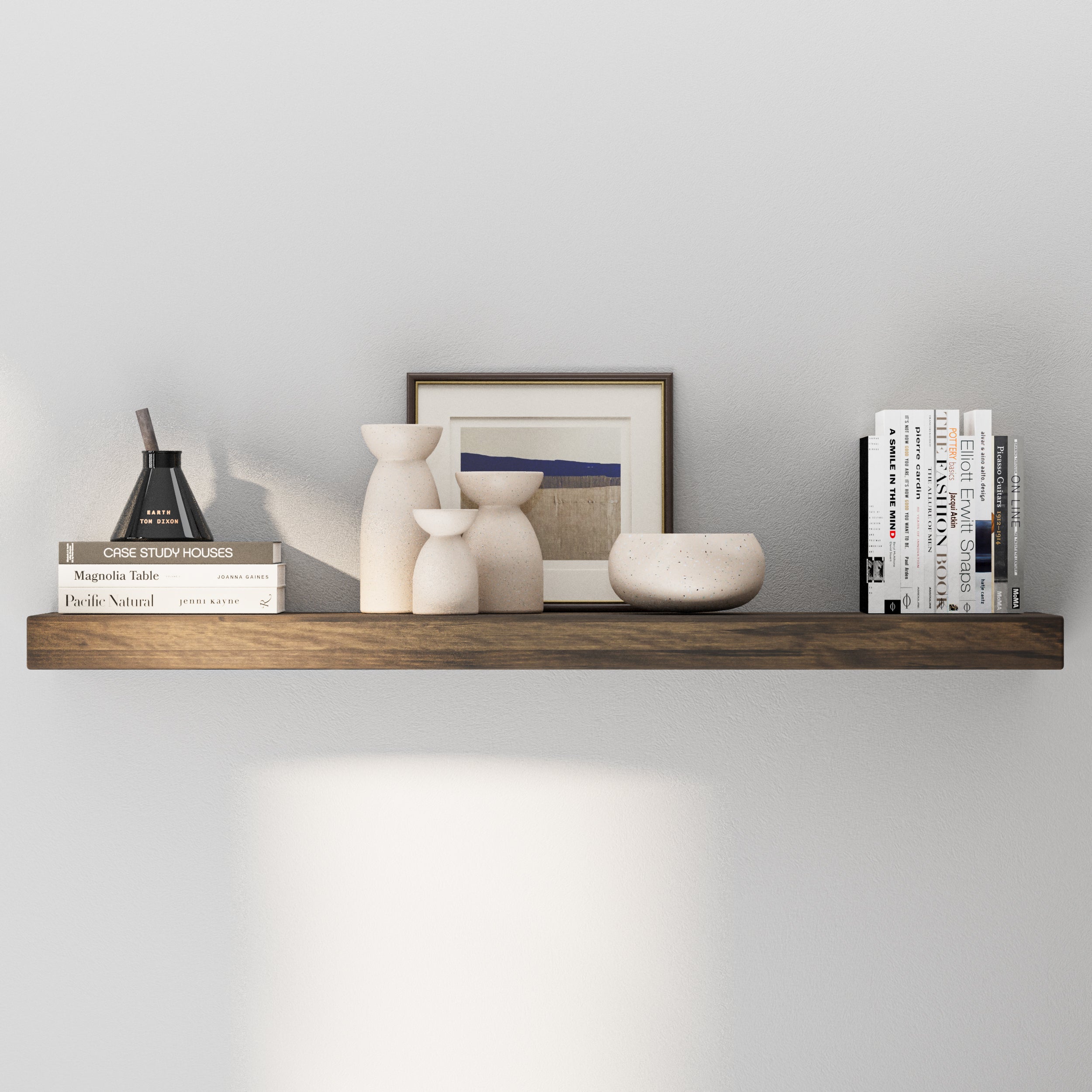 A single dark wooden floating shelf displays minimalist décor with neutral-toned vases, books, and framed art, offering a calm and refined modern aesthetic.