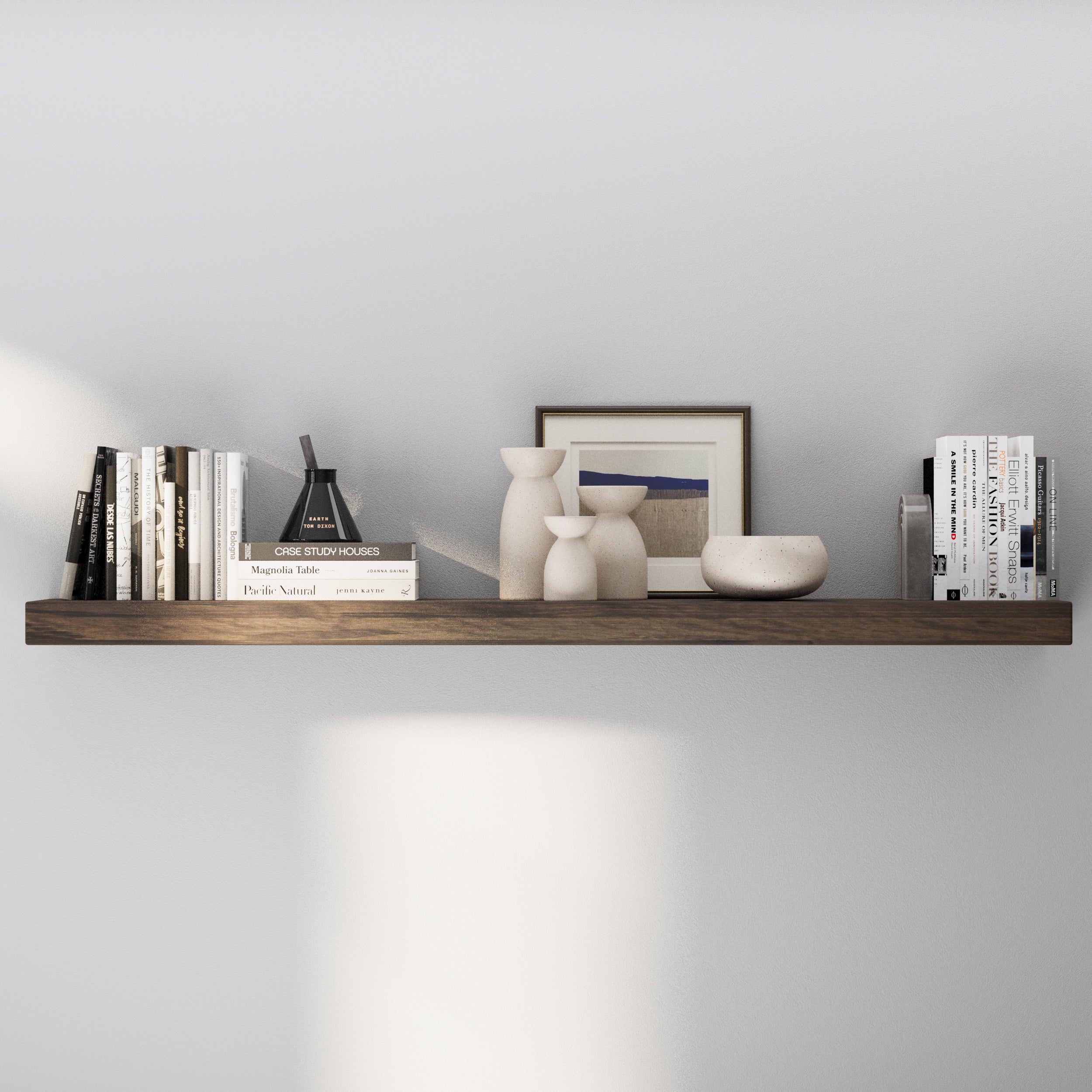 A single dark wooden floating shelf 60 inch long displays minimalist décor with neutral-toned vases, books, and framed art, offering a calm and refined modern aesthetic.