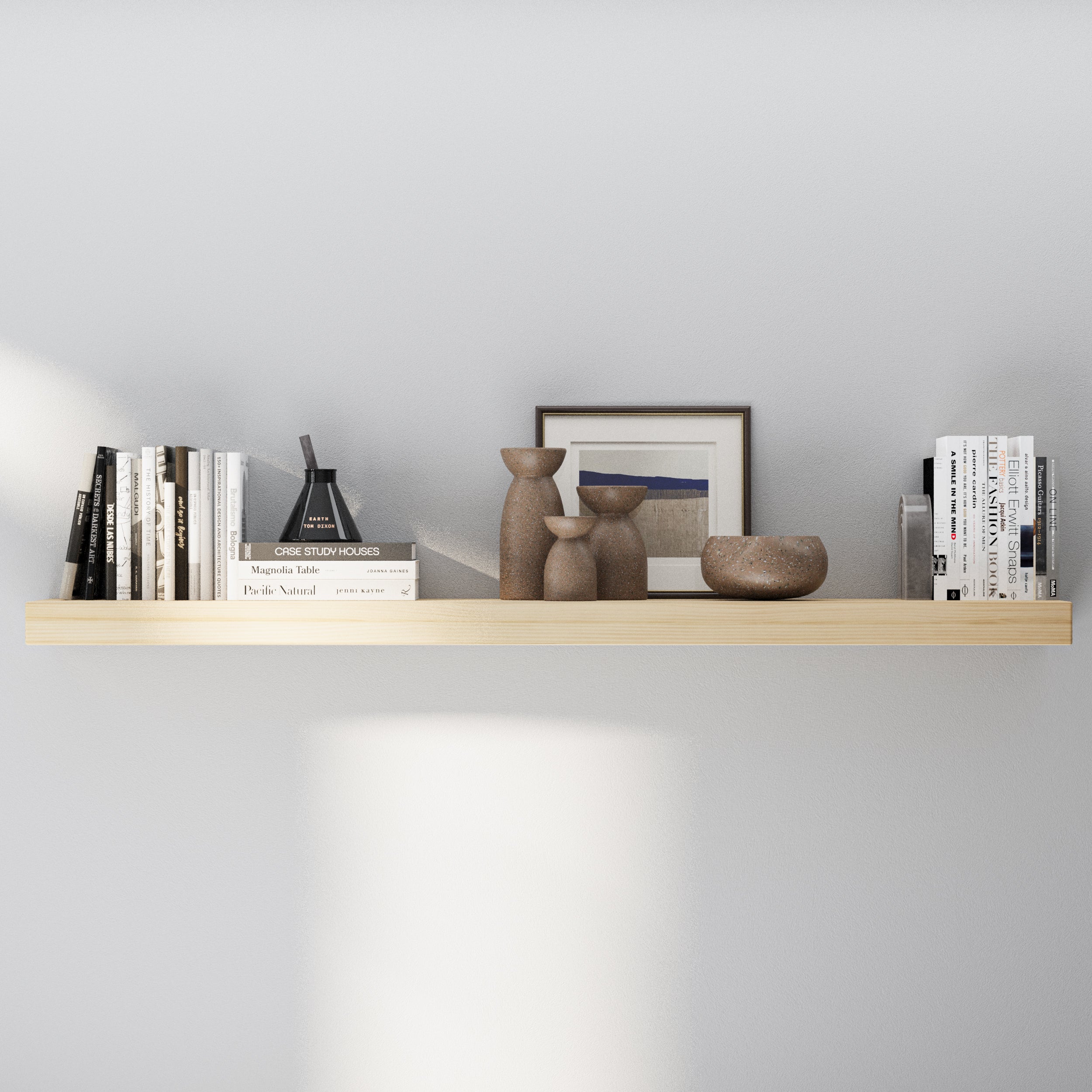 A single long floating shelf in a natural wood finish styled with ceramic vases, neutral-toned books, and framed wall art, offering a minimalist and airy decorative look.