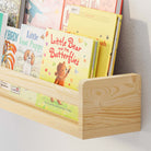 Close-up of the natural wood nursery shelf holding children's books, showcasing its sturdy construction and smooth finish. The detailed view highlights the craftsmanship and practical design of the shelf.