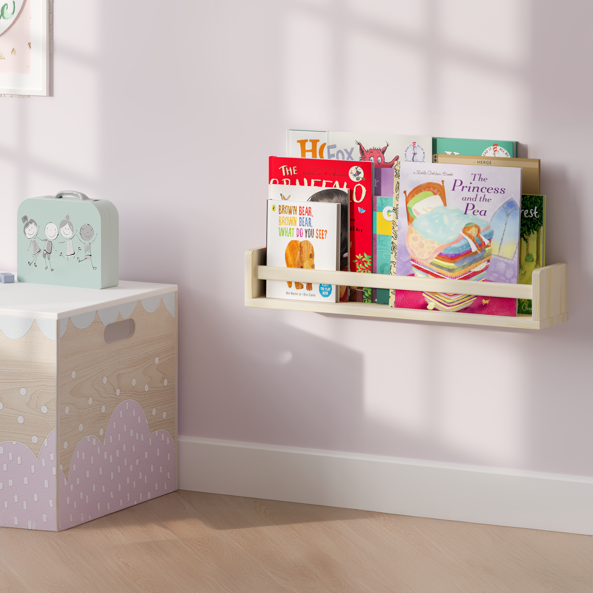 A natural wood wall shelf filled with children's books, mounted on a soft pink wall beside a decorative storage box. The setup creates a charming and organized reading nook for kids.