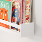Close-up of a floating kids shelf white with children's books, highlighting the clean lines and modern design, making it a versatile addition to any room.