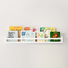 The floating kid shelf white filled with an array of colorful children's books, demonstrating its ample storage space and aesthetic appeal.