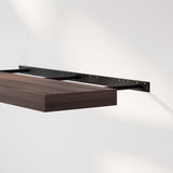 Close-up of a floating bookshelf walnut showcasing its sleek design and sturdy metal bracket that remains hidden, emphasizing a clean and uncluttered aesthetic.
