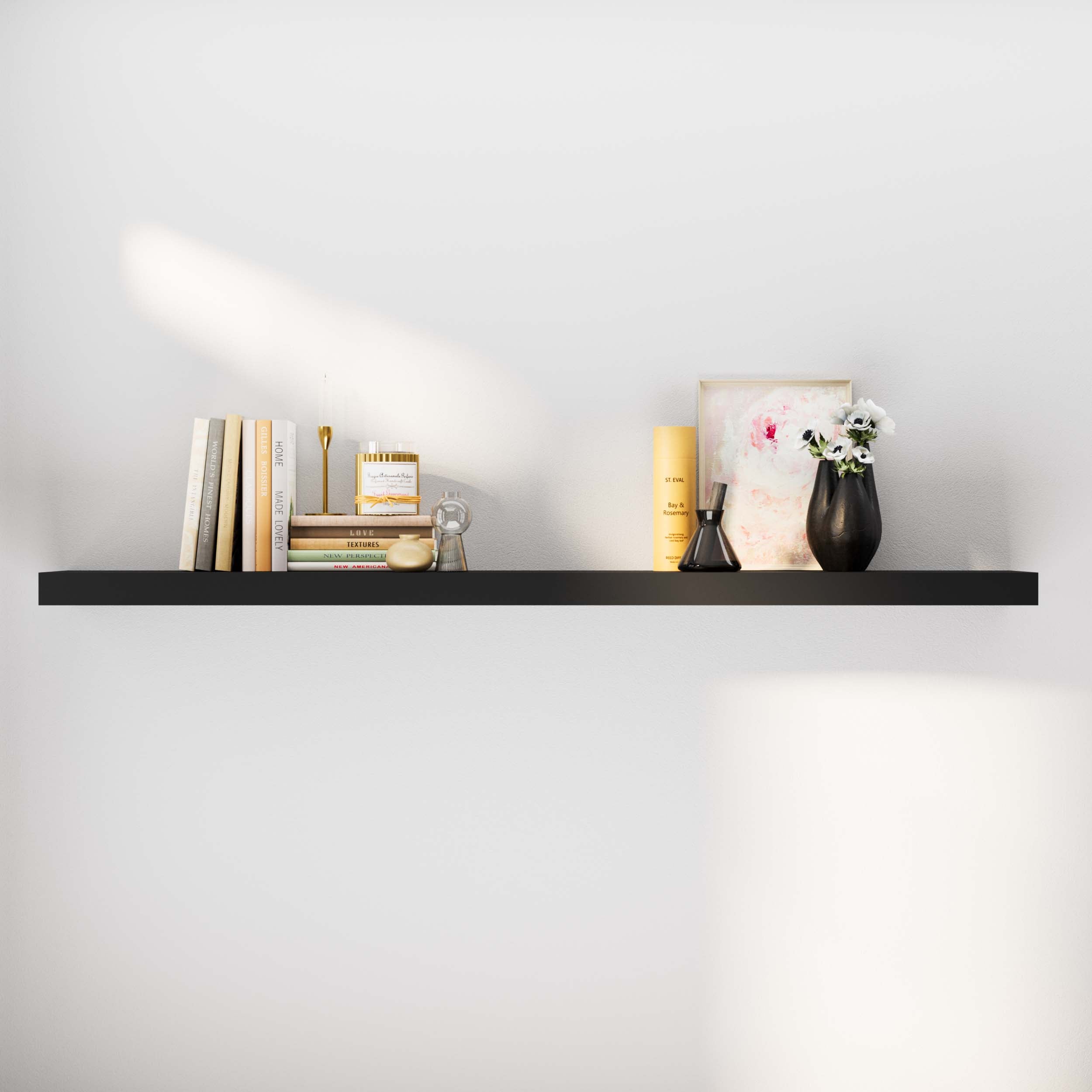 A stylish black floating shelf holds a vase, books, and a decorative frame, enhancing a minimalistic room decor.