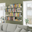 Green accent wall with white 17 inch display shelves above a sofa, displaying books, vases, and art, blending practicality with modern style.