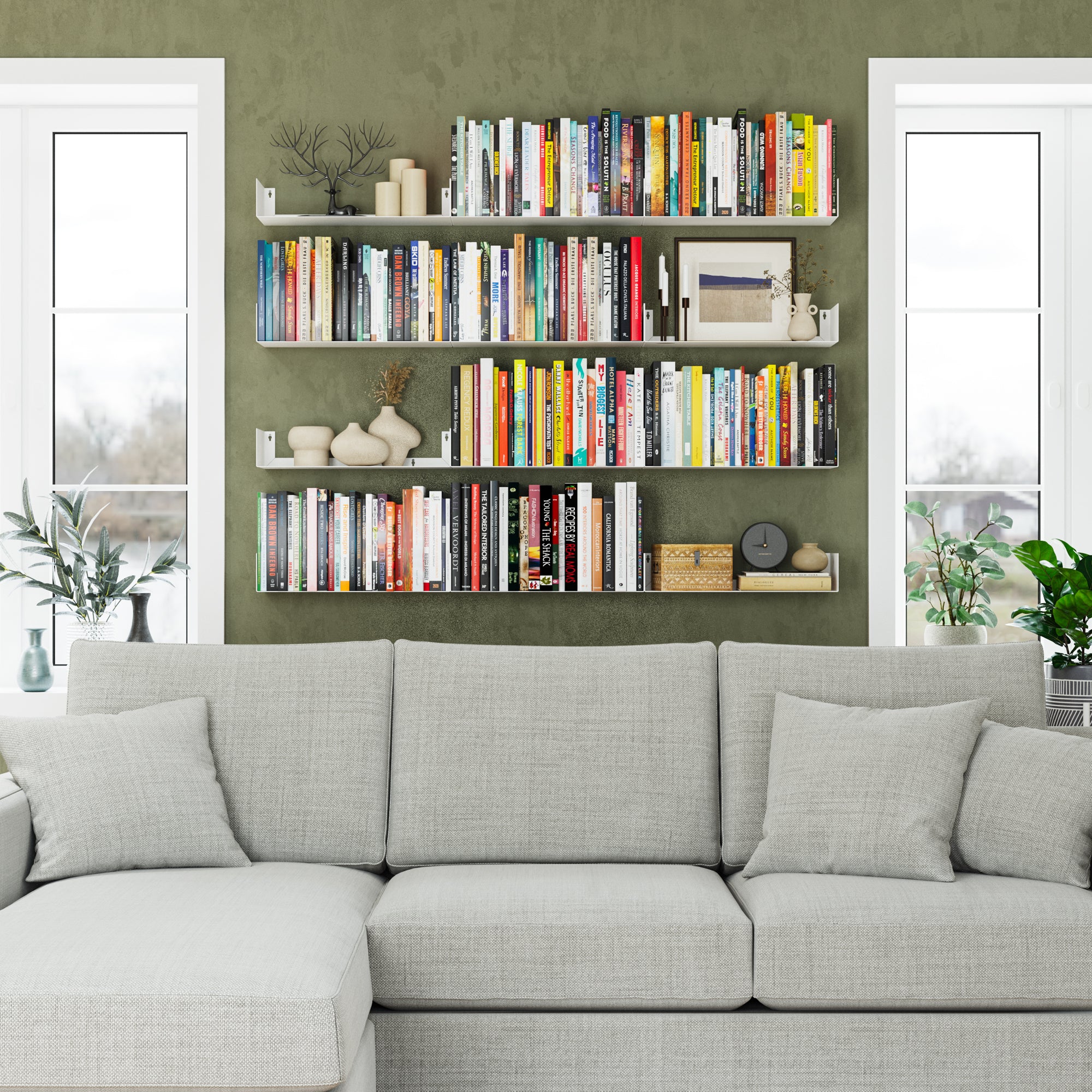 Green accent wall with white 17 inch metal shelves above a sofa, displaying books, vases, and art, blending practicality with modern style.