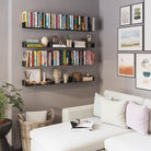 A cozy reading nook with three black floating shelves displaying books and décor, perfect for adding storage and style in a compact living room corner.