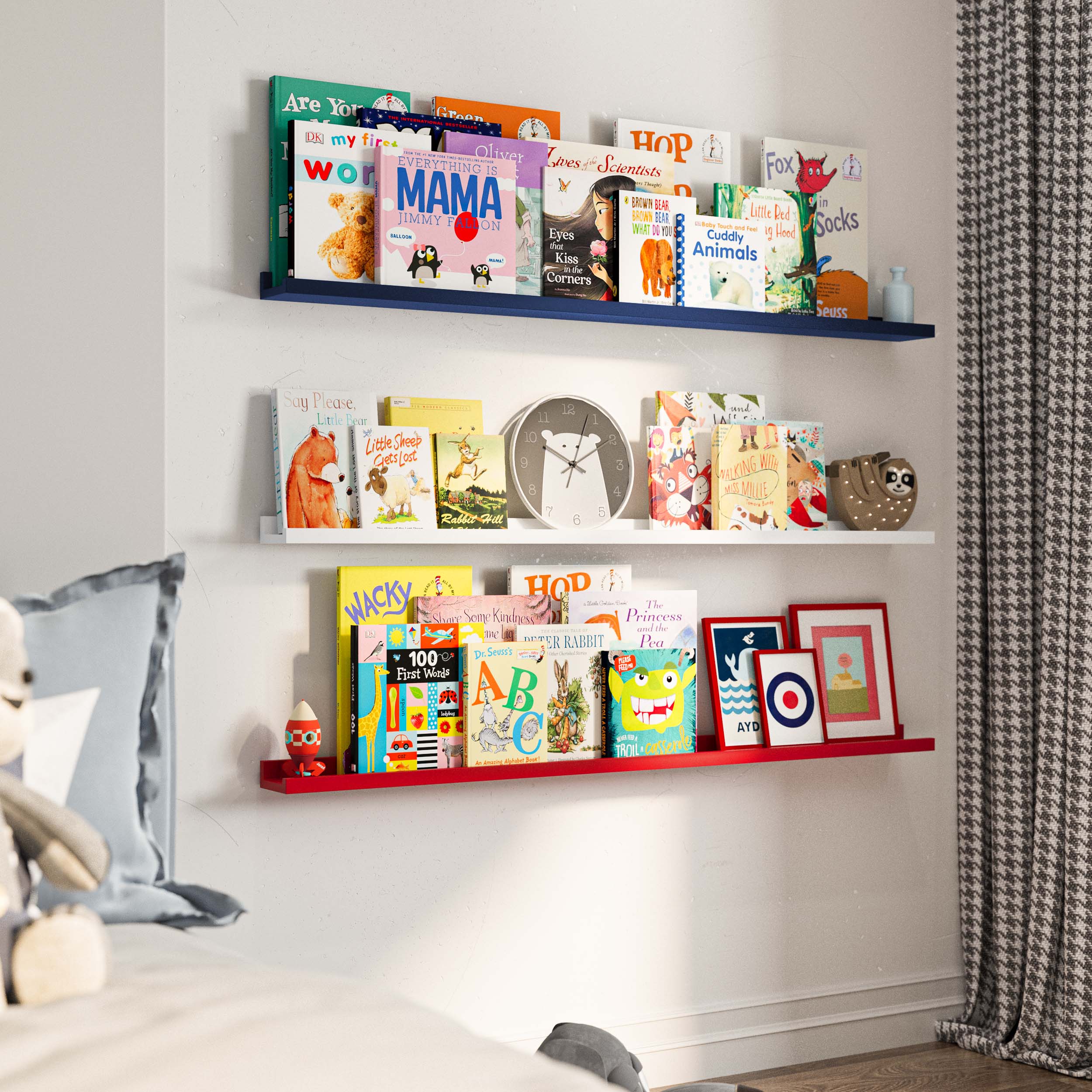 three wall-mounted shelves in a child's room. The shelves are filled with children's books, organized neatly in a way that each book's cover is visible. The color scheme of the shelves remains consistent with the top shelf in blue, the middle one in white, and the bottom one in red. This image is taken from a slightly different angle, offering a closer view of the books and the shelf arrangement. The plush toy in the bed remains partially visible, adding a touch of softness to the setting.