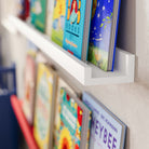 a close-up of one of the white shelves, focusing on the detail of the shelf's edge and how the books are neatly organized, emphasizing the clean and functional design of the shelving unit.