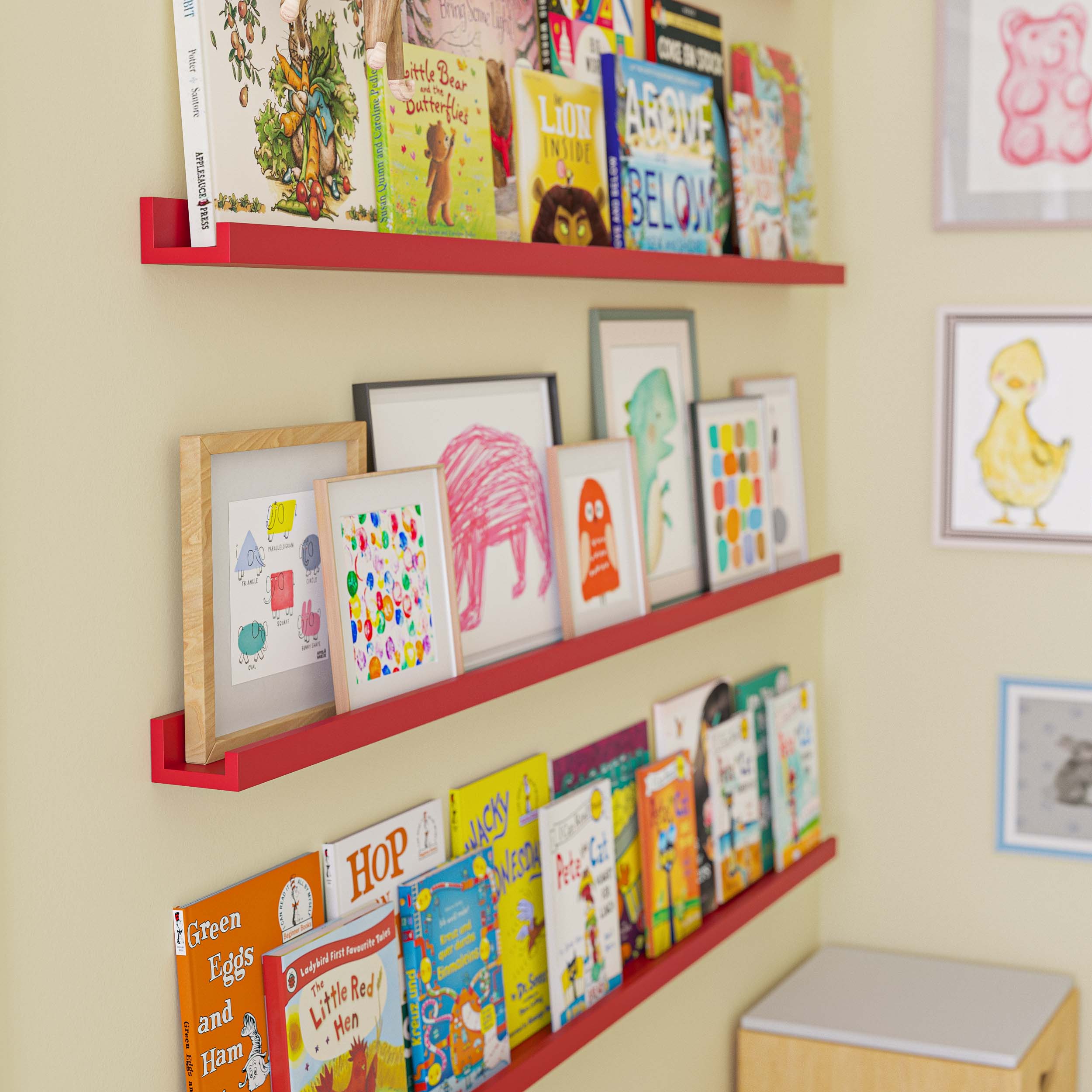 A close-up of the same setup as the first image, focusing on the colorful wall-mounted red shelves filled with books. The image highlights the details of the books and decorations on the cute shelves, such as framed pictures and small decorative items.