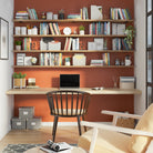 A home office setup featuring a custom wooden desk paired with hanging office shelves filled with books and decor against a warm, inviting backdrop.