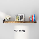 A 48" long rustic wall shelf is decorated with floral artwork, books, and a vase. The natural wood grain and black side brackets create a clean, elegant display perfect for minimalist and modern interiors.