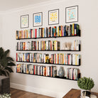 Home library setup with black floating shelves lined with books, decorated with minimalist art on top, blending organization with modern decor.