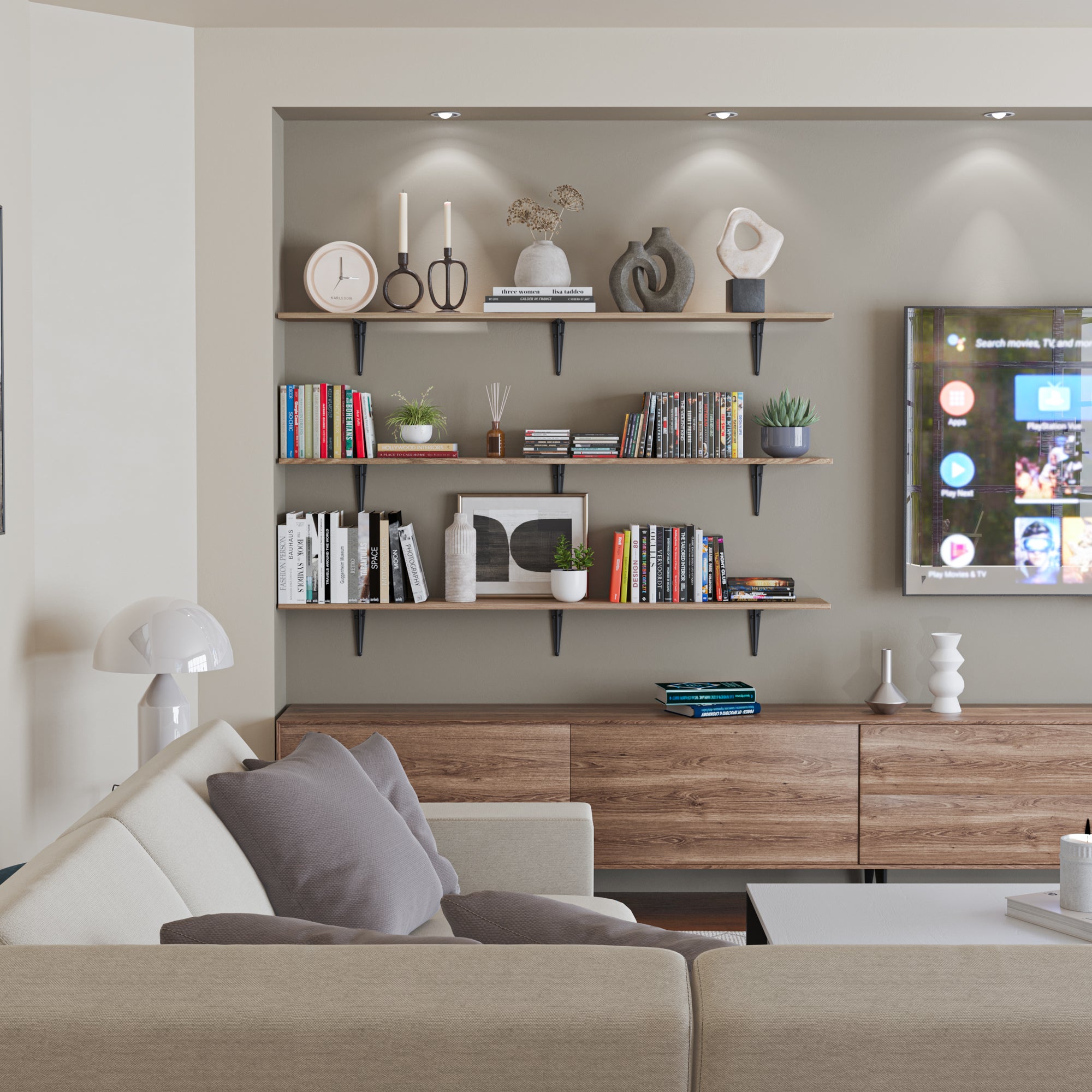 Built-in style wall shelving near a TV setup, showcasing books, sculptural decor, candles, and greenery under recessed lights—functional and cozy for modern media rooms.